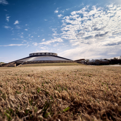 A vast grassy field extending out from a very large circular building, the Muscogee (Creek) Nation District Court building.